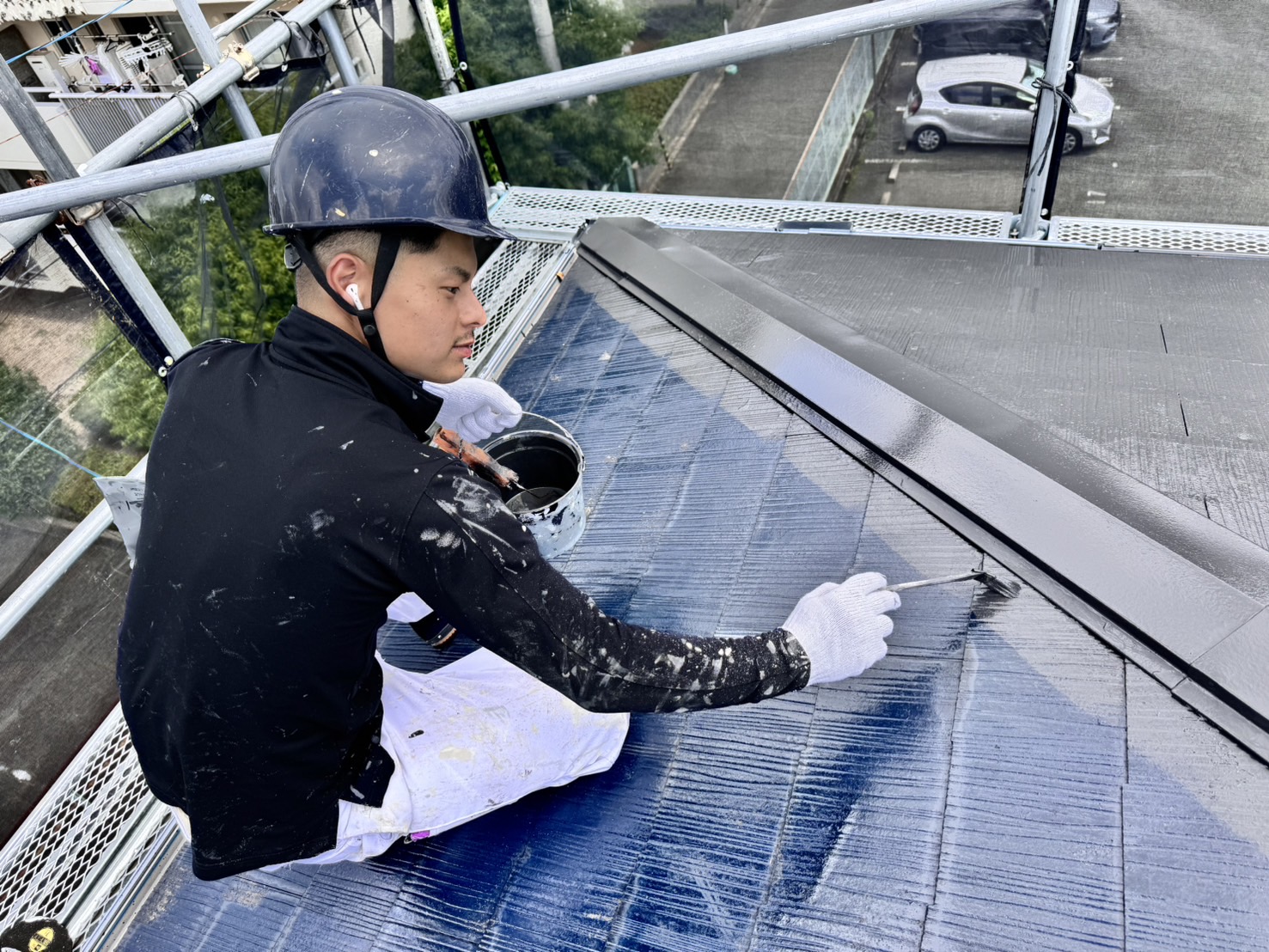 屋根をローラーで塗装する職人
